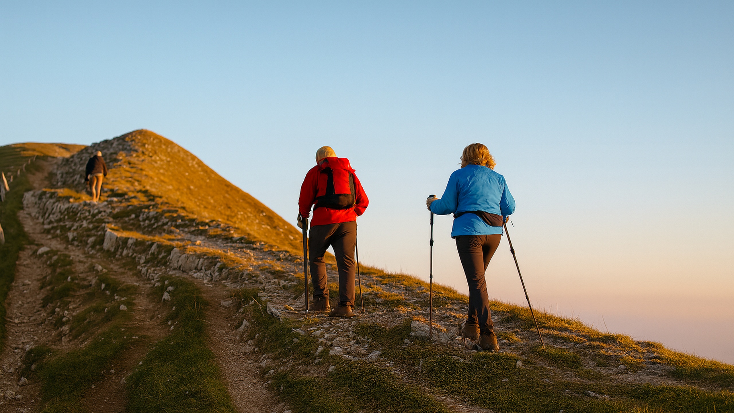 Couple hiking up a mountain trail at sunrise, symbolizing strength, perseverance, and recovery through regenerative and pain medicine